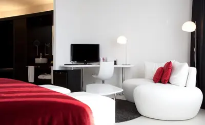 a white room with a white chair and a television at Hotel Porta Fira 4* Sup in Hospitalet de Llobregat