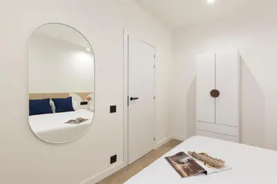 a white bedroom with a mirror on the wall at Diagonal Apartments by Olala Homes in Barcelona