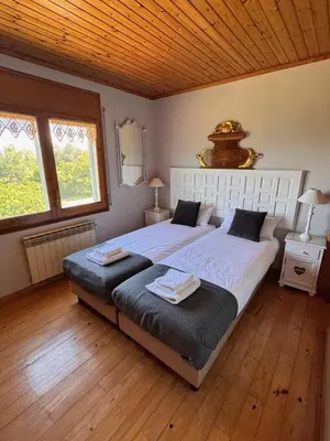 a bedroom with two beds and two windows at Finca La Pedrera in Capellades
