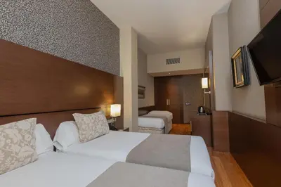 a hotel room with two beds and a television at Barcelona Hotel Colonial in Barcelona