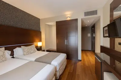 a hotel room with two beds and a television at Barcelona Hotel Colonial in Barcelona