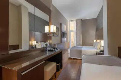 a hotel room with a bedroom with a bed and a desk at Barcelona Hotel Colonial in Barcelona