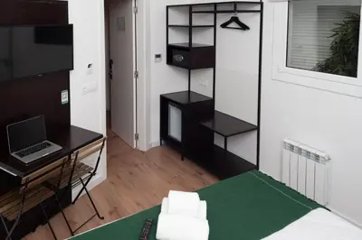 a room with a bed and a desk and a laptop at Bailén Green House in Barcelona