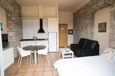 a bedroom with a bed and a table and a kitchen at Urbi Apartments in Manresa