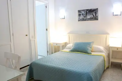 a bedroom with a bed with a blue and yellow blanket at Hostal Ramos in Barcelona