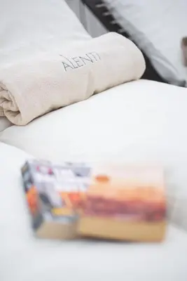 a pillow on a bed with a magazine on it at Alenti Sitges Hotel in Sitges