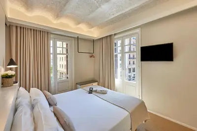 a bedroom with a large white bed and a tv at The Moods Catedral Hostal Boutique in Barcelona