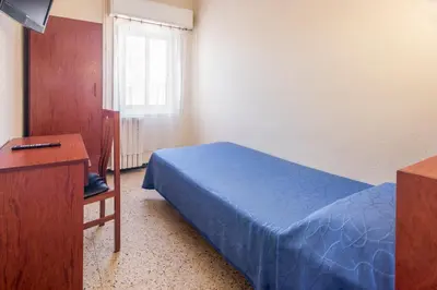 a bedroom with a bed and a dresser and a television at Hostal Solimar in Badalona