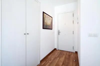 a hallway with white walls and a door and wooden floors at Inside Barcelona Apartments Sants in Barcelona
