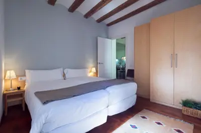 a bedroom with a large white bed and wooden cabinets at Inside Barcelona Apartments Esparteria in Barcelona