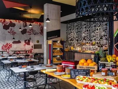 a woman holding up a drink in front of a table of food at ibis Styles Barcelona City Bogatell in Barcelona