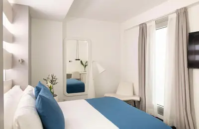 a white bedroom with a blue bed and a mirror at Allegro Barcelona in Barcelona