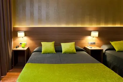 a bedroom with a large green bed with two lamps at Bed and Breakfast El Pekinaire in Calella