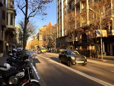 a car is driving down a city street with buildings at Charm Rambla Catalunya in Barcelona
