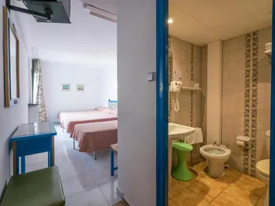 a room with two beds and a bathroom with a toilet at Checkin Garbí in Calella
