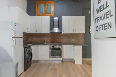 a kitchen with white cabinets and a washer and dryer at Centric Gracia Apartments in Barcelona