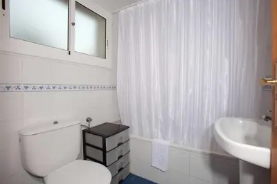 a white bathroom with a toilet and a sink at Apartamentos Sunway Tara in Sitges