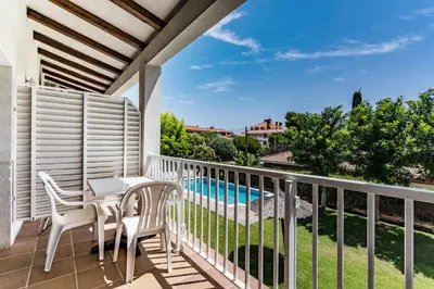 a balcony with a table and chairs and a swimming pool at Apartamentos Sunway Tara in Sitges