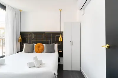 a bedroom with two beds with white sheets and orange pillows at TSA La Mare in Barcelona