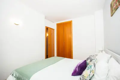 a bedroom with a bed with white sheets and purple pillows at Sitges Center & Beach Espalter in Sitges