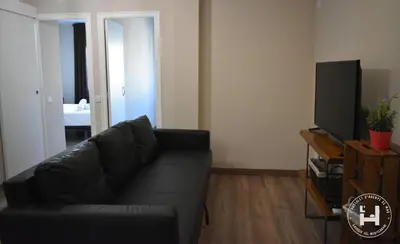 a living room with a black couch and a television at L'Hostalet d'Arenys de Mar in Arenys de Mar