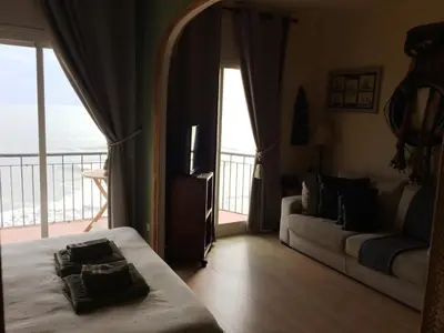 a bedroom with a bed and a couch and a balcony at Sitges Beach Panorama in Sitges