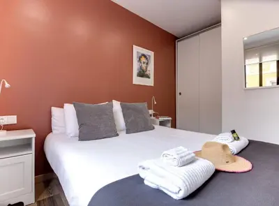 a bedroom with a large white bed with towels on a table at City&Beach Apartments in City Center in Barcelona