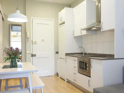 a kitchen with white cabinets and a table with a vase of flowers at Cozy Gracia 2 bedrooms in Barcelona
