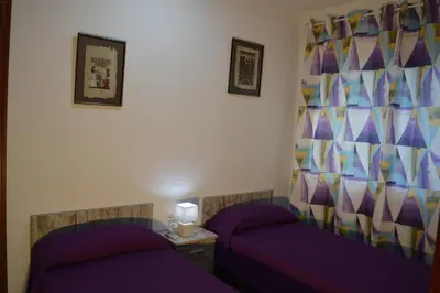 two beds in a room with purple sheets at Vista Cunit in Cubelles