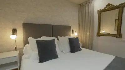 a bedroom with a white bed with pillows and a mirror at Sarriá - Sant Gervasi in Barcelona