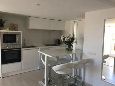 a kitchen with a table and some white chairs at Panoramic Apartments Sitges in Sitges