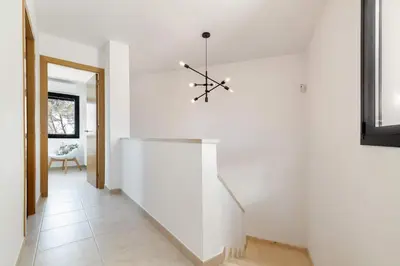 a hallway with white walls and a staircase with a chandelier at Luxury Sitges Hills Villa in Olivella
