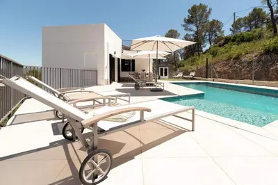 a pool with a table and chairs and an umbrella at Luxury Sitges Hills Villa in Olivella