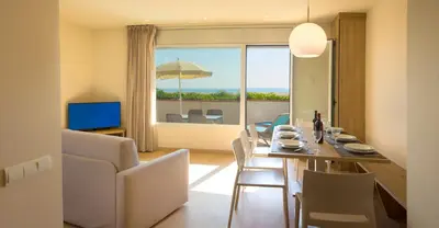 a dining room and living room with a table and chairs at Apartamentos Voramar in Castelldefels