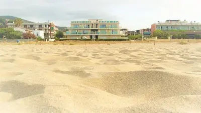 a sandy beach with buildings in the background at Apartamentos Voramar in Castelldefels