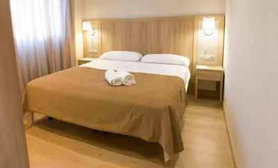a hotel room with a bed with a towel on it at Apartamentos Voramar in Castelldefels