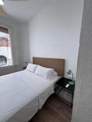 a bedroom with a large white bed and a table at Calma House Barcelona in Barcelona