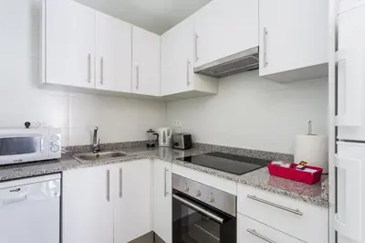 a white kitchen with white cabinets and a sink at Contemporary Apartment Near Camp Nou and Fira Barcelona in Hospitalet de Llobregat