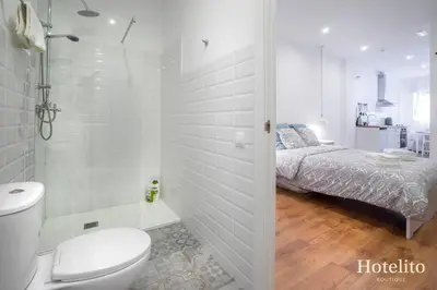 a white bathroom with a toilet and a bed at Hotelito Boutique Camp Nou in Hospitalet de Llobregat