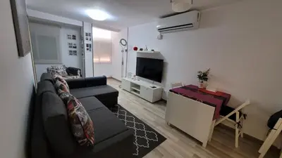 a living room with a black couch and a tv at APARTAMENTS B O D CoLLBLANC in Hospitalet de Llobregat