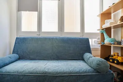 a blue couch in a living room with windows at My Home in Barcelona in Barcelona
