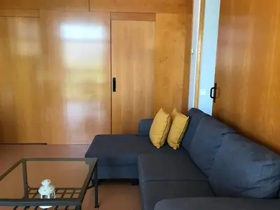a living room with a blue couch and a glass table at Barceló Cornellà in Cornellà de Llobregat