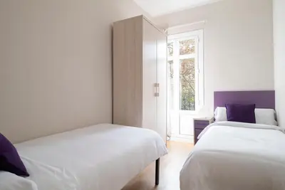 two beds in a white room with a window at The Family Host - Lost Garden Ciutadella Park in Barcelona