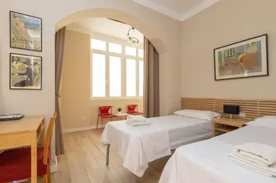 a room with two beds and a table and a window at ApartEasy - Family 4-Bedroom Apartment in Barcelona