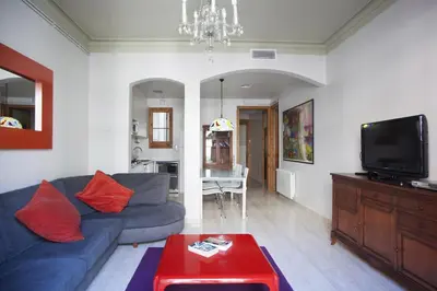 a living room with a blue couch and a tv at ApartEasy - Authentic Family Apartment in Barcelona
