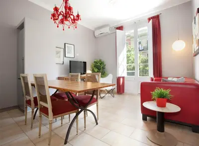 a living room with a dining room table and a red couch at ApartEasy - Family Sant Antoni apt. in Barcelona