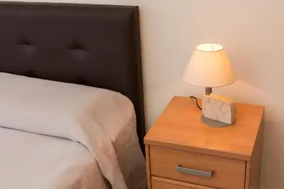 a lamp on a wooden nightstand next to a bed at ApartEasy - Family Apartment Sant Antoni in Barcelona