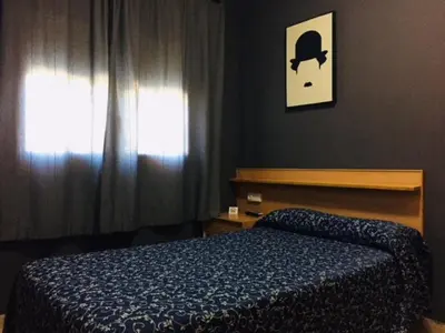a bedroom with a blue bed and a window at Hostal del Carmen in Terrassa