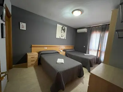 a small room with two beds and a table at Hostal del Carmen in Terrassa