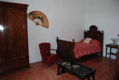 a bedroom with a bed and a red chair at Can plana de baix in San Pol de Mar